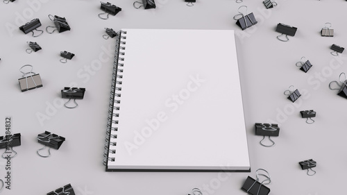 Blank spiral notebook with black binder clips on white table