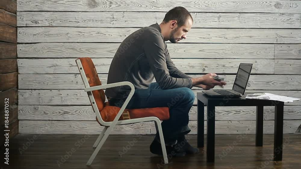A man sits at a laptop and thinks the money A man sits at a laptop and thinks the money