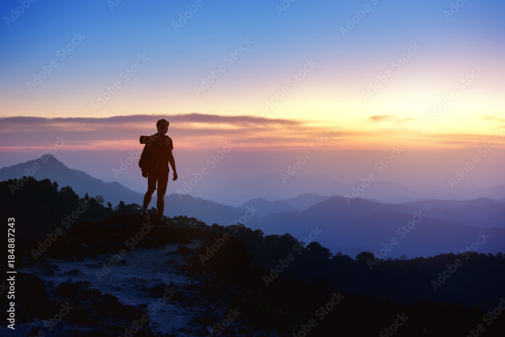 Man's silhouette on sunset mountains backdrop