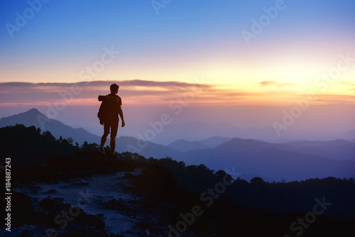 Man's silhouette on sunset mountains backdrop
