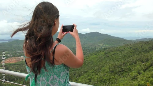 Girl in a Dress Take a Picture of a Green Hills of Jungels on Her Phone photo