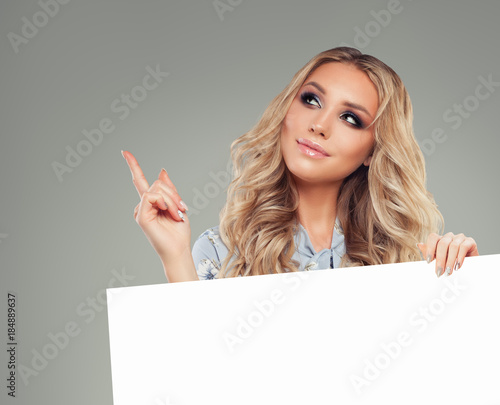 Beautiful Woman Pointing her Finger and Holding White Empty Paper Card Background