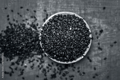 Close up of black sesame seed,Sesamum indicum in a small plate on a wooden surface.