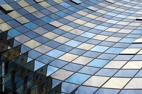 Perspective view of the modern glass building facade with reflections on the windows. Architectural pattern