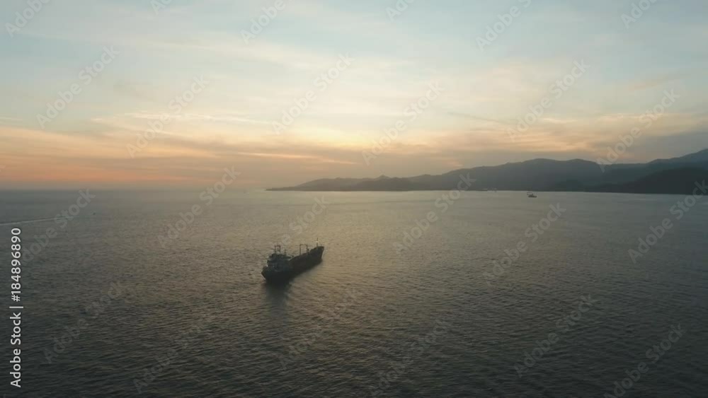 Aerial view Cargo ship in the sea at sunset. Sunset over the sea. Flying over the blue ocean with blue water, sky. Bali,Indonesia.4K video. Travel concept. Aerial footage Aerial view Cargo ship in the sea at sunset. Sunset over the sea. Flying over the blue ocean with blue water, sky. Bali,Indonesia.4K video. Travel concept. Aerial footage