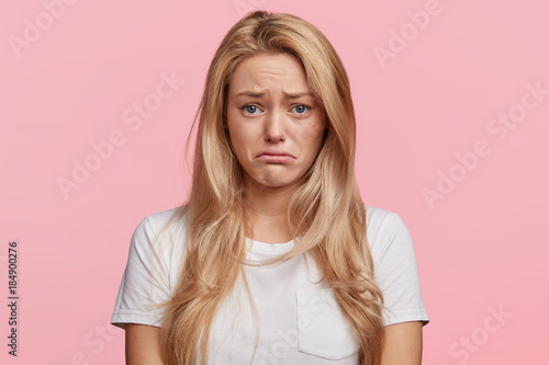 Obraz na plátne Portrait of displeased upset female frowns face as going to cry, being discontent and unhappy as can`t achieve goals, isolated over pink studio background