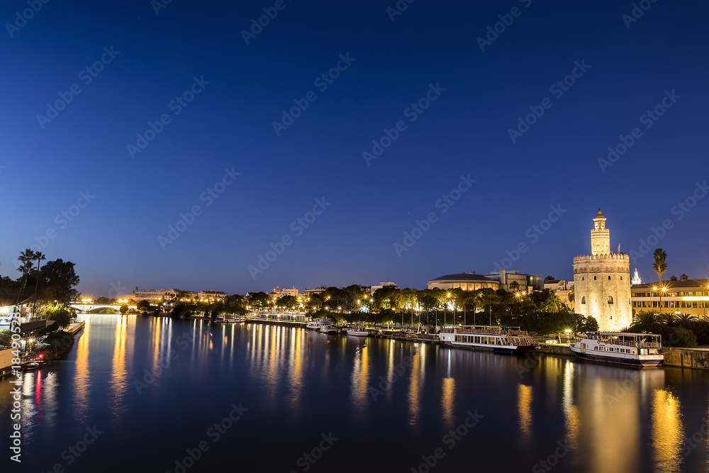 Long exposure Golden tower (Torre del Oro) at sunset from the other side of the Guadalquivir river at night, Seville (Andalusia), Spain.