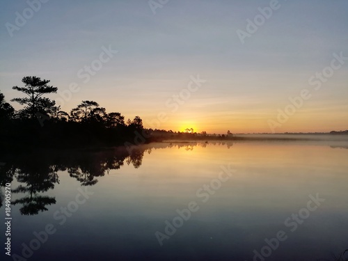 Reflection of the forest over the lake. Lake and forest in morning sunrise.