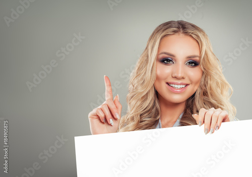 Beautiful Woman with Blonde Hair Pointing Up and Holding White Paper Card