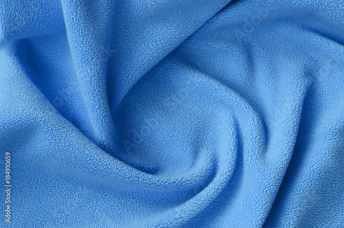 The blanket of furry blue fleece fabric. A background of light blue soft plush fleece material with a lot of relief folds photo