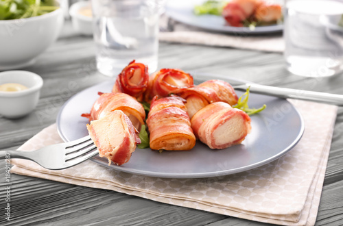 Plate with bacon wrapped chicken nuggets on table