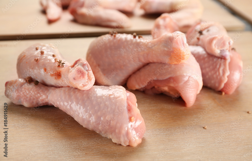 Wooden board with raw chicken legs on table, closeup Wooden board with raw chicken legs on table, closeup