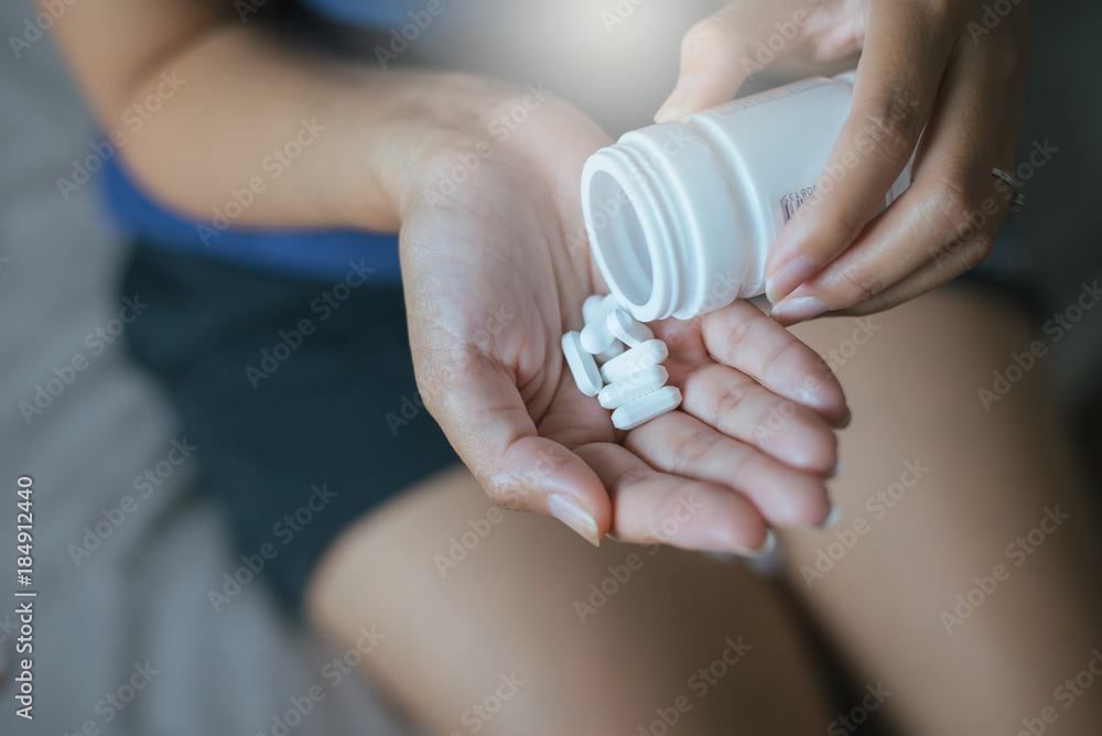 Woman hands with pills on spilling pills out of bottle Woman hands with pills on spilling pills out of bottle