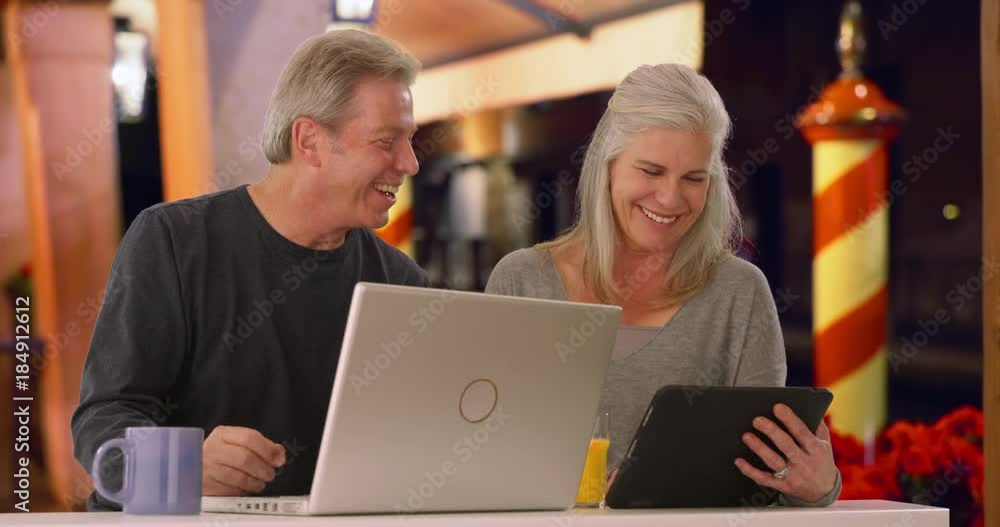 Caucasian man and his wife browse the internet at outdoor coffee shop at night Caucasian man and his wife browse the internet at outdoor coffee shop at night