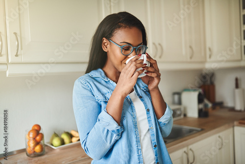 Slika na platnu Young African woman enjoying a coffee in her kitchen