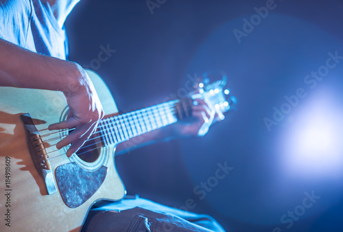 the hand of man playing acoustic guitar, close-up, flash of light, a beautiful light in the background photo
