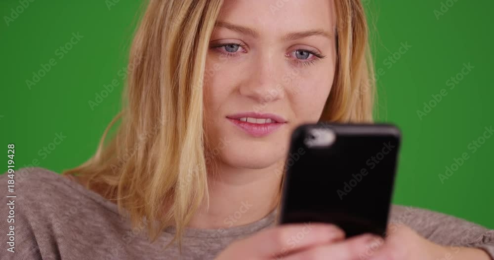 Close-up portrait of beautiful blonde millennial woman with blue eyes using smartphone device on green screen. On green screen to be keyed or composited. Close-up portrait of beautiful blonde millennial woman with blue eyes using smartphone device on green screen. On green screen to be keyed or composited.