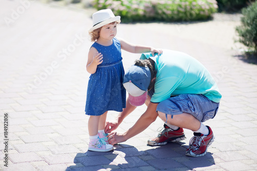 A father helping his little daughter with her shoes.