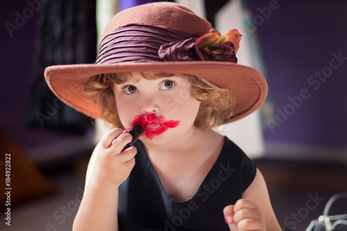 Little girl trying mothers lipstick. Growing up concept.