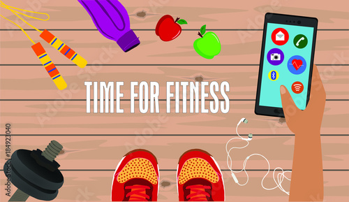 Fitness, healthy and active lifestyles concept. Dumbbells, sport shoes, smart phone with earphone and water bottle  on wooden gym floor with word time for fitness. Hand holding smartphone with icons