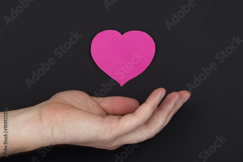 Heart in a palm on dark background with copy space