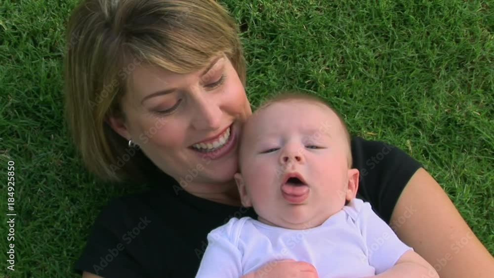 Mother and baby outdoors laying in grass Mother and baby outdoors laying in grass