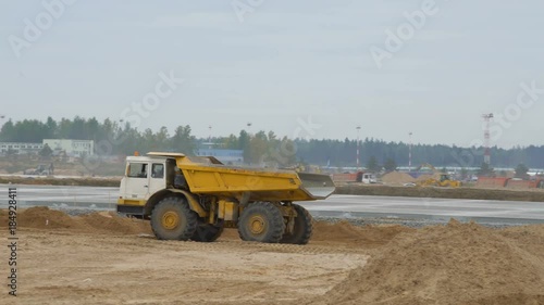 Large quarry dump truck rides, driving on construction site. Concreting of airport runways roads, highway. Construction machinery works on runway construction of national airport Minsk, MSQ photo