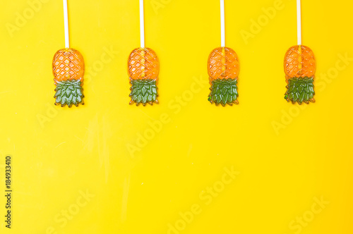 Fototapeta Naklejka Na Ścianę i Meble -  Candy in the form of pineapple on a yellow background. Pattern flat lay