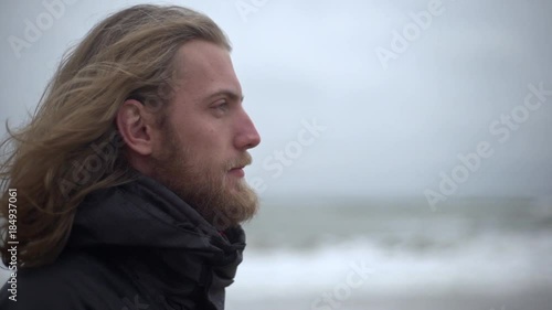 Portrait in profile of manly male explorer with long brown hair taking pleasure in force of nature breathing fresh cold air looking ahead in slow motion