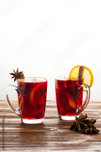 Two glasses of hot mulled wine with cinnamon, oranges, cranberries and anise. 