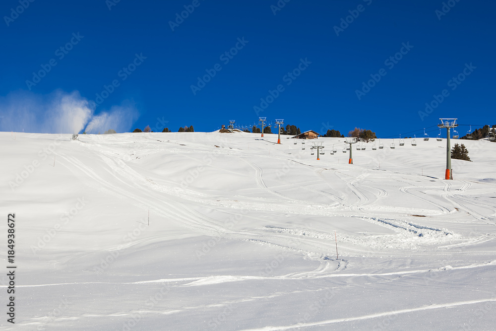 Chairlift without people. Artificial snowing ski slope by Snow cannon maker.