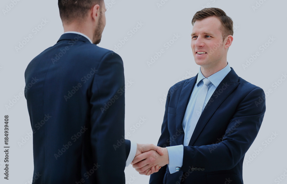 Business colleagues sitting at a table during a meeting with two male executives shaking hands Business colleagues sitting at a table during a meeting with two male executives shaking hands