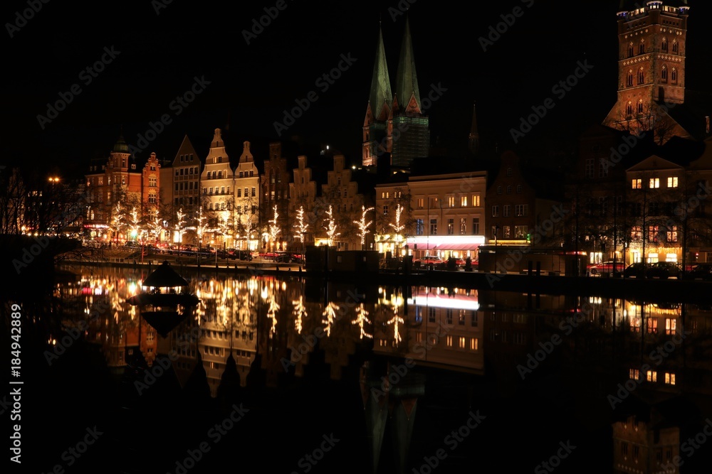 historic gable houses and church towers in festive christmas lights in the medieval old town of Lübeck at night