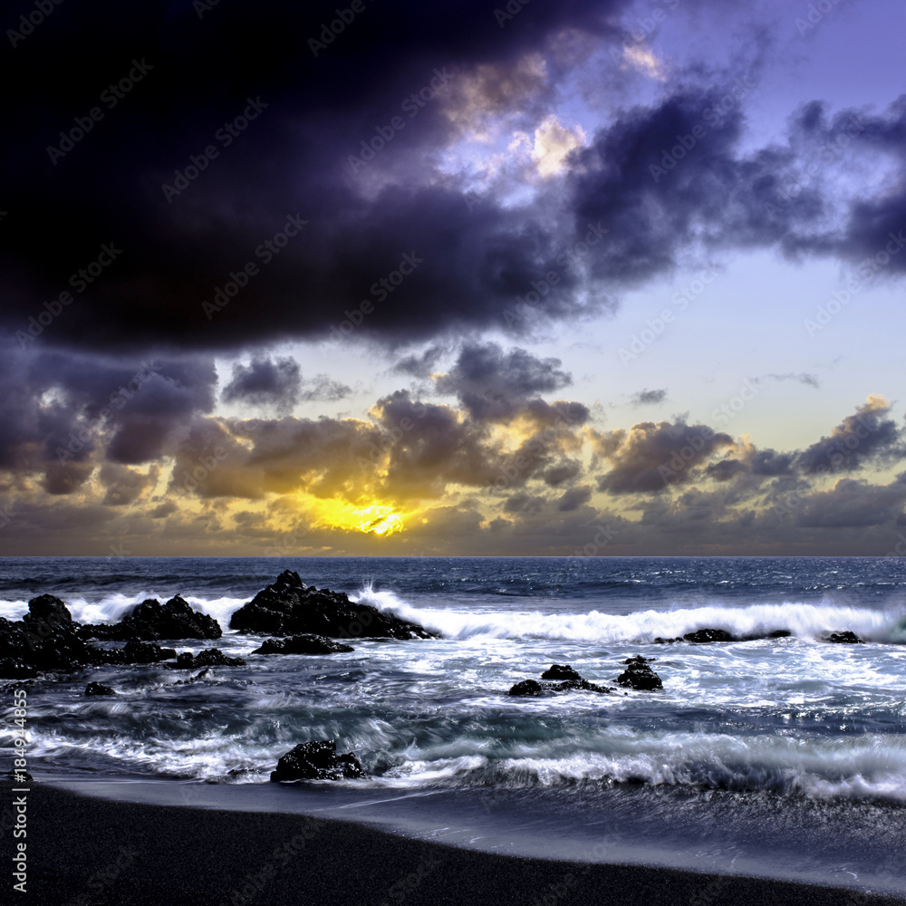 Obraz premium Sunrise over the ocean before storm - black volcanic beach near El Golfo, Lanzarote, Canary Islands, Spain