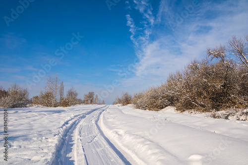 Countryside road through winter field with forest on a horizon. Artistic picture. Beauty world.
