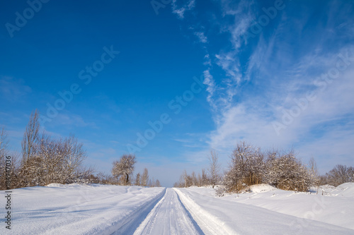 Countryside road through winter field with forest on a horizon. Artistic picture. Beauty world. © olenatur