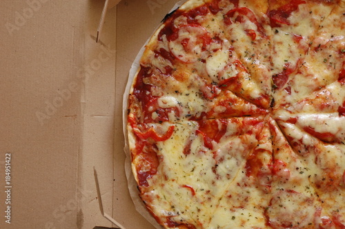 A large pizza in a cardboard box is a top view.