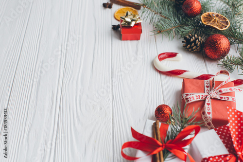Christmas composition. Gifts, pine cones, fir branches, candy, spices and other decorations on wooden white background. Flat lay, top view.