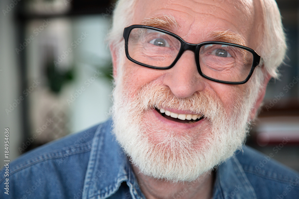 Close up portrait of old bearded smiling man looking at camera with excitement. He is open-eyed and amazed Close up portrait of old bearded smiling man looking at camera with excitement. He is open-eyed and amazed