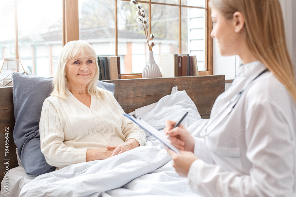 Obraz premium Nurse taking care of senior woman writing prescription retirement concept