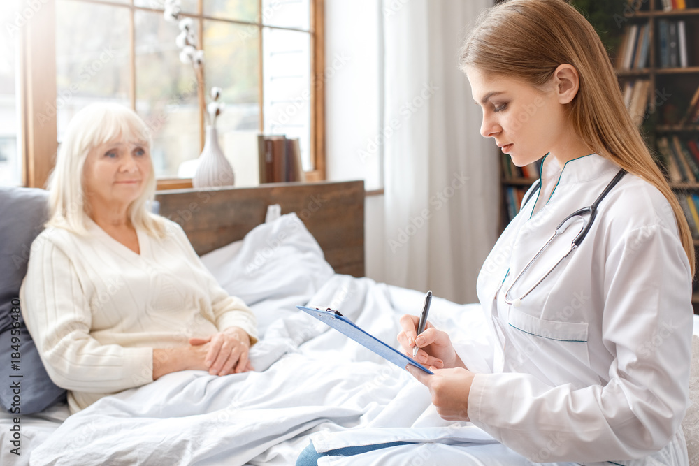 Obraz premium Nurse taking care of senior woman writing prescription retirement concept