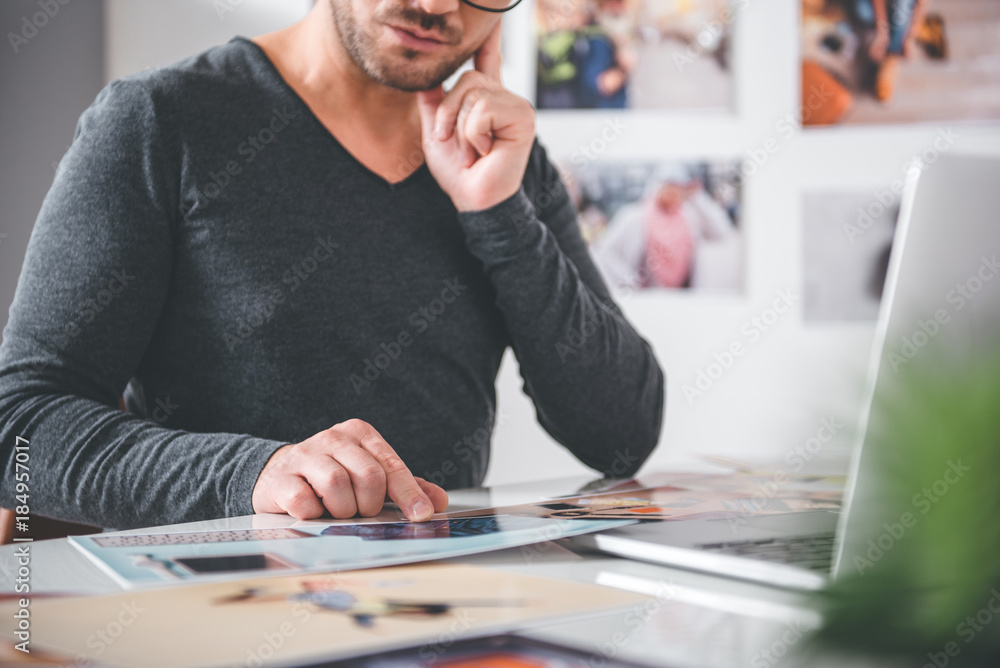 Focus on close up hand of serene bearded man showing on picture while situating at table in office. Labor concept Focus on close up hand of serene bearded man showing on picture while situating at table in office. Labor concept