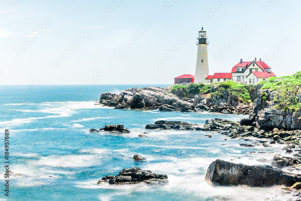Cliff rocks side view shore with Portland Head Lighthouse in Fort Williams park in Cape Elizabeth, Maine during summer day