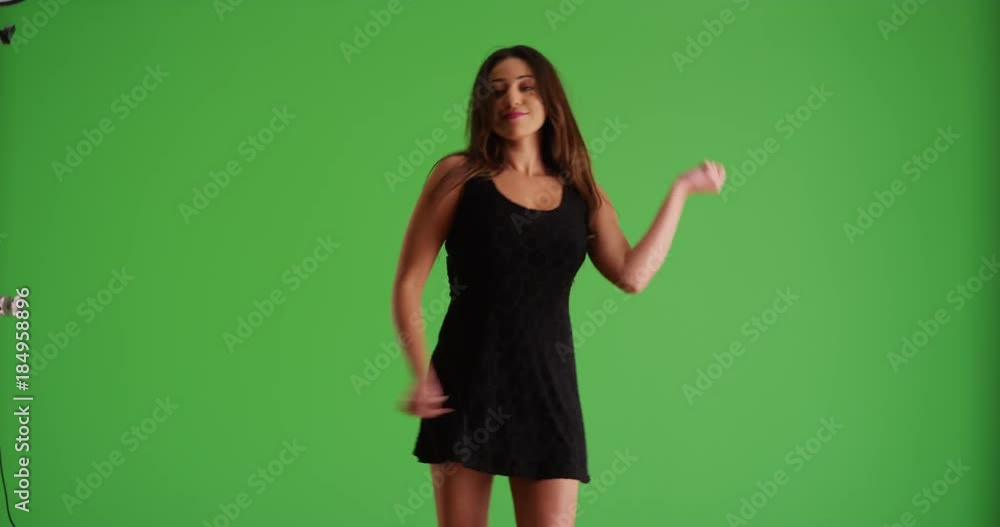 Portrait of young Latina female in short black dress dancing on green screen. On green screen to be keyed or composited. 