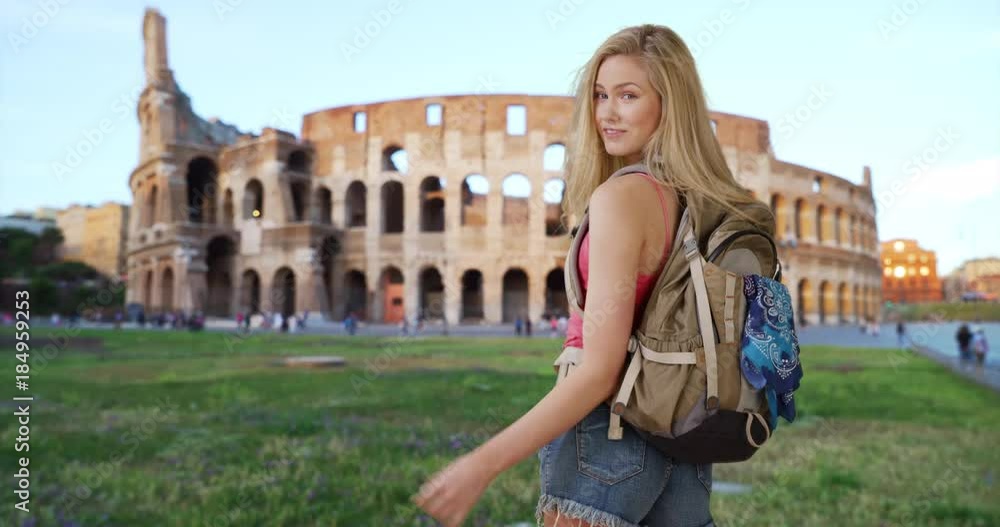 Attractive Caucasian tourist near Roman Colosseum motions camera to follow her Attractive Caucasian tourist near Roman Colosseum motions camera to follow her