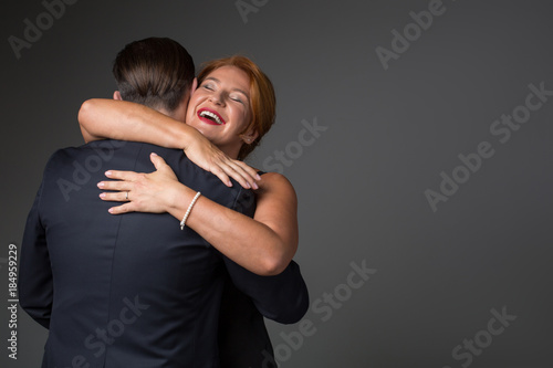 Portrait of exited woman embracing her husband with love and smiling. Focus on male back in suit. Isolated and copy space