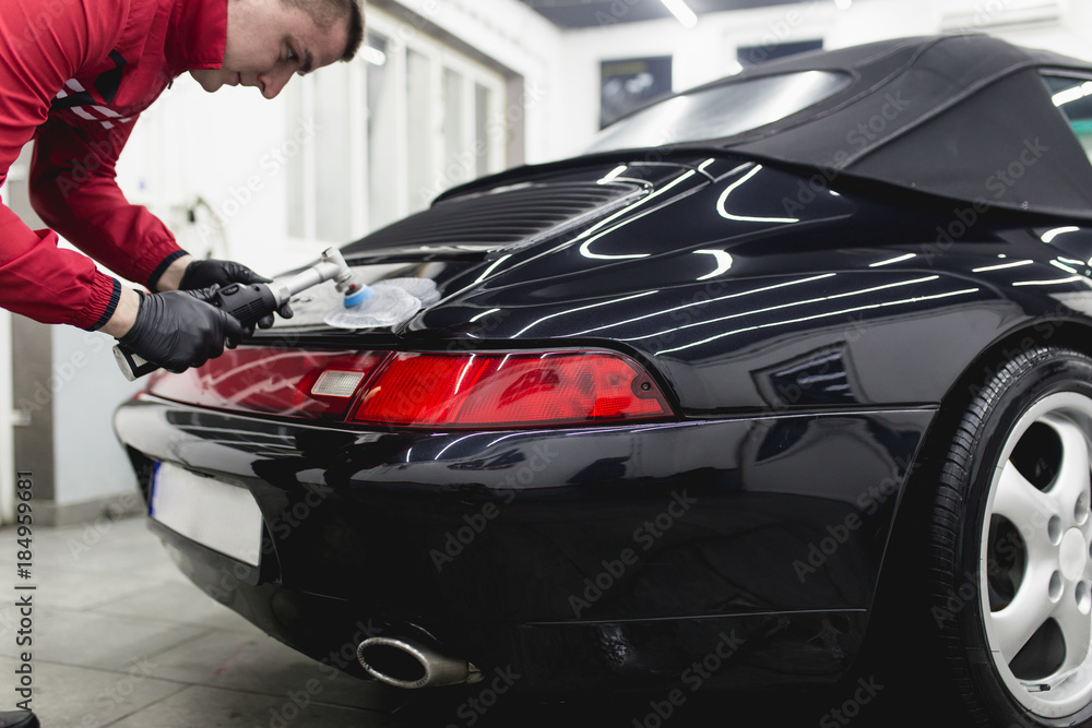 Naklejka premium Car detailing - Worker with orbital polisher in auto repair shop. 
