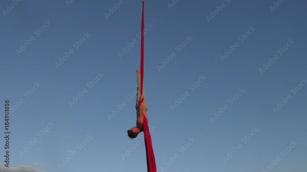 Male aerial acrobat shows tricks on canvases in the sky. Male aerial acrobat shows tricks on canvases in the sky.