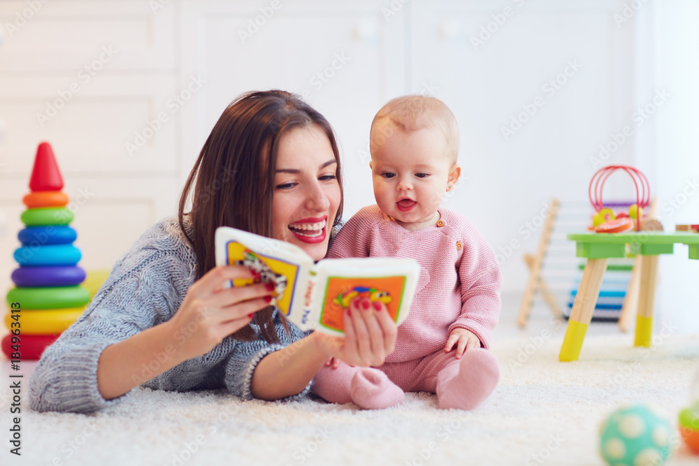 cute mother and daughter playing together, reading first book - obrazy, fototapety, plakaty 