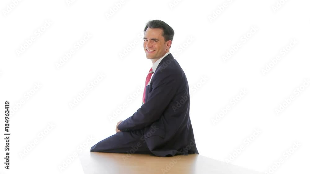 Businessman sitting at edge of table looking over shoulder Businessman sitting at edge of table looking over shoulder